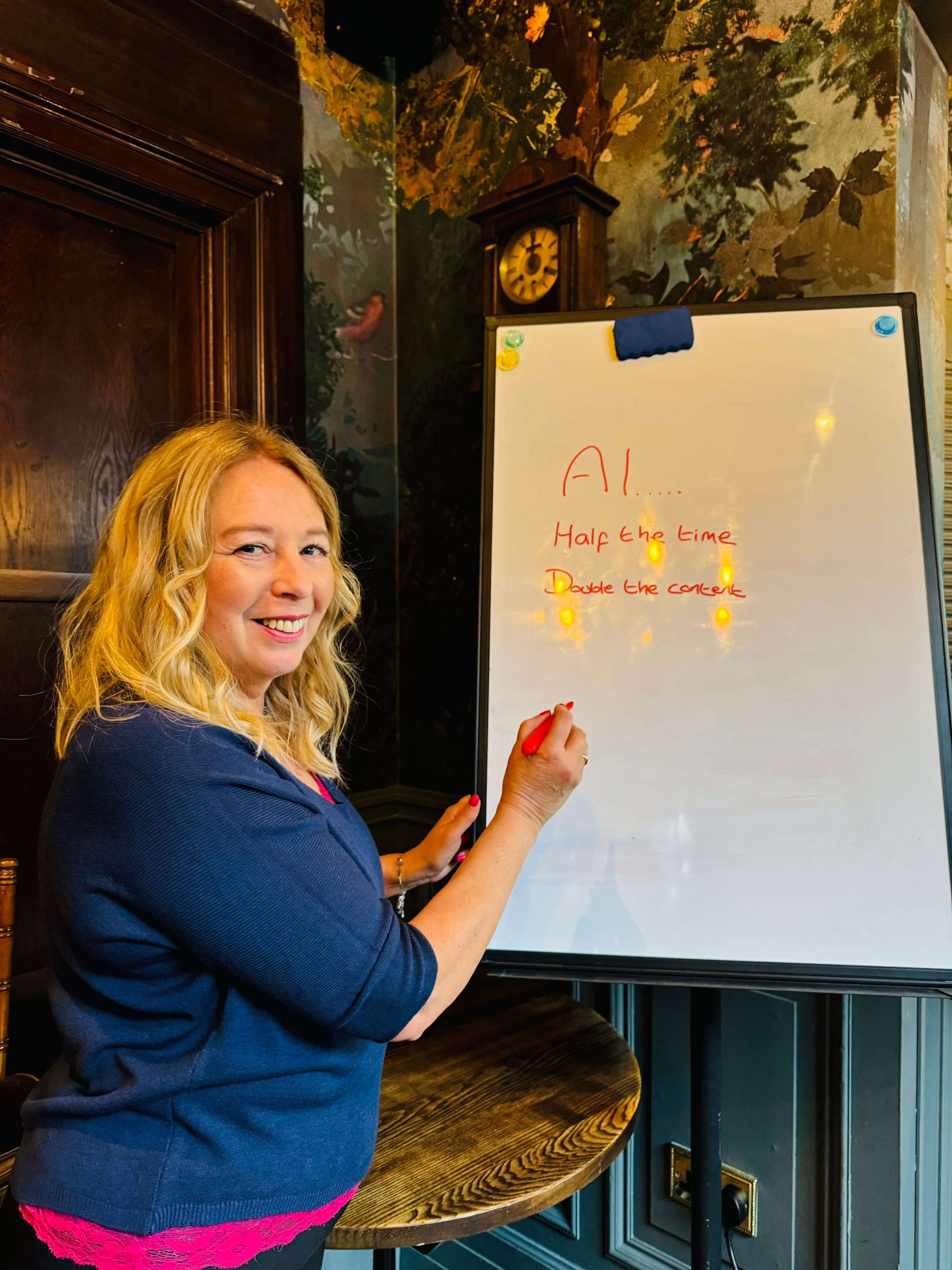 Jacqueline Leake writes “AI…” notes on a whiteboard with a red marker in a wood-panelled room.